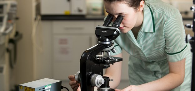 Student veterinary nurse looking through a microscope